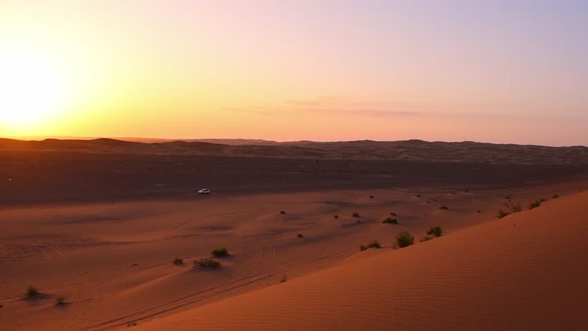 Panning view car stands by desert at sunset with scenic golden dunes in Kashan, Iran