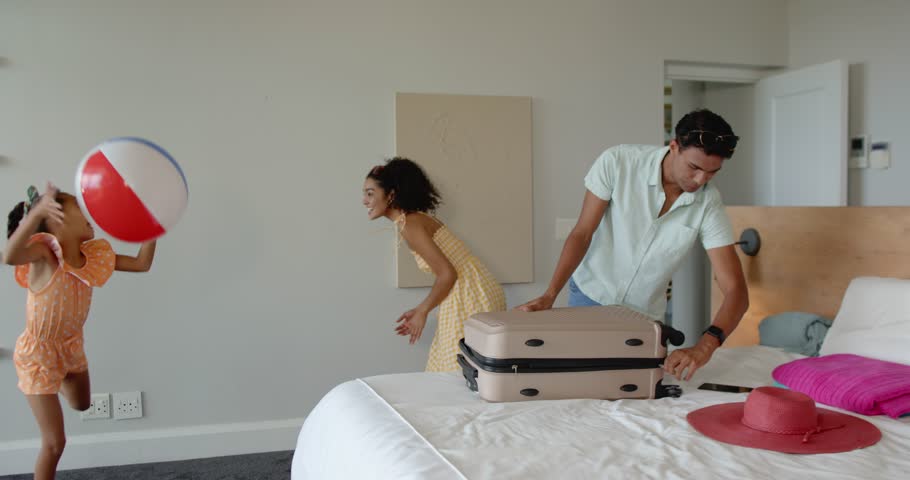 Diverse family planning first holiday inside modern home with beach ball and suitcase. Family, vacation, preparation, relaxation, childhood, minimalist, togetherness, adventure