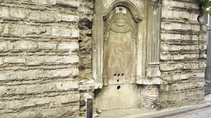 Cinematic historic Ottoman Baroque architecture with Rococo influences, showing old sealed doorway on textured stone wall, covered with green climbing plants 18th to 19th century urban heritage detail