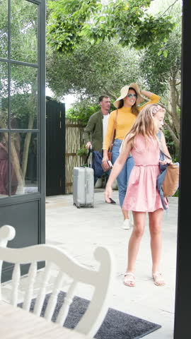 Vertical video: Girl stepping into dining room leading family wheeling suitcase exploring interior. Family, travel, adventure, lifestyle, outdoor, candid, vertical video