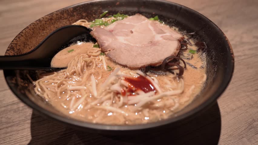 Close-up view of the pork broth based Japanese ramen topped with slow cooked charsiu, green onions, fungus and sprouts.
