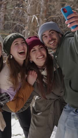 Group of happy friends capturing a selfie in a snowy forest, enjoying each other's company in a cheerful winter scene
