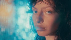 Portrait of young beautiful woman looking calmly at camera against glowing blue bokeh background - Powered by Shutterstock - Get 15% off with code: PIKWIZARD15