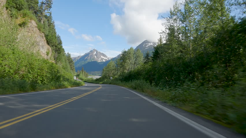 POV Driving a car on asphalt road in Alaska. Blue sky on sunny day