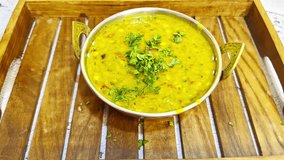 Delicious Lentil Served in Metal Bowl on Wooden Tray, Cooked Pulse is topped with aromatic tempering of spices, Golden Legumes Dish Enhance Aroma Garnish, Curry Plated inside Hygienic Indian Cookhouse - Powered by Shutterstock - Get 15% off with code: PIKWIZARD15
