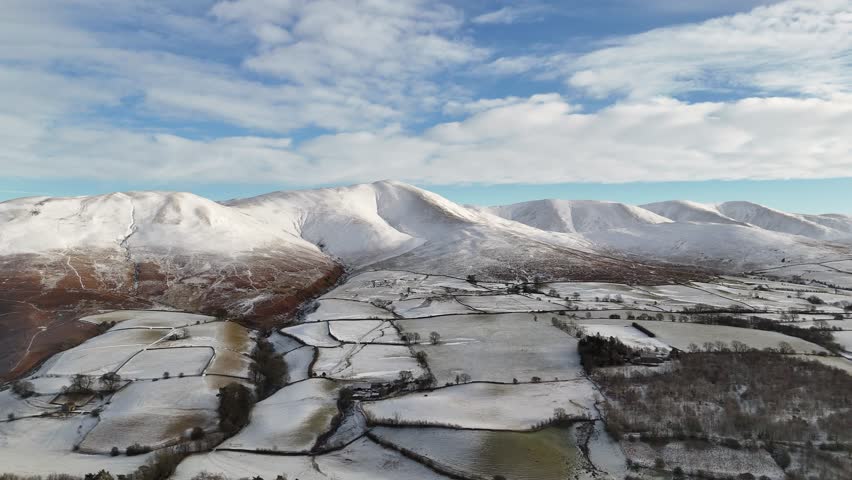 A beautiful winter landscape featuring snow-covered mountains and fields under a blue sky with clouds. Part 2.