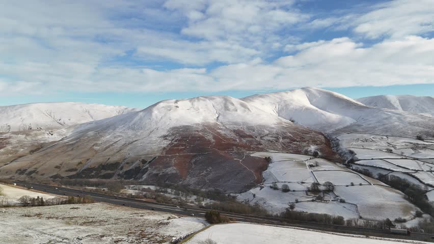 A beautiful winter landscape featuring snow-covered mountains and fields under a blue sky with clouds. Part 1.