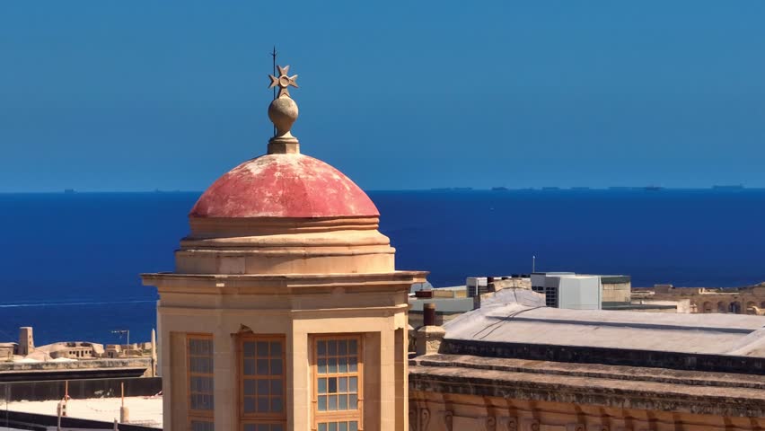 Closeup view of maltese cross on dome catholic church in Valletta and Mediterranean sea, ships on background. Malta island