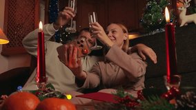 Cheerful couple sitting on sofa, clinking glasses with champagne, and congratulating family and friends online on video call during christmas holidays in cozy, decorated living room - Powered by Shutterstock - Get 15% off with code: PIKWIZARD15