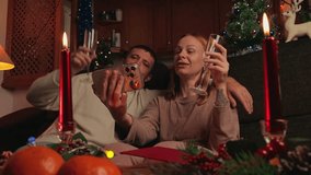 Young couple celebrating christmas at home, making video call to their family or friends while drinking champagne and wishing them happy holiday in cozy, decorated living room - Powered by Shutterstock - Get 15% off with code: PIKWIZARD15