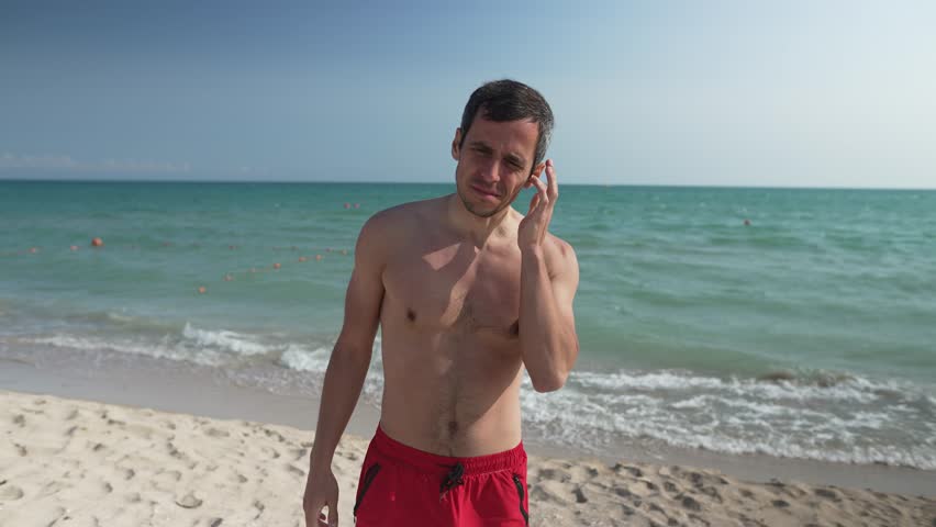 Man Shaking Water Out of Ears After Swimming at the Beach