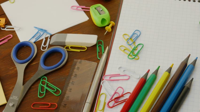 Creative workspace with colorful pencils, eraser, paper clips, push pins. Essential office and school supplies provide organization and efficiency. Notebook with cells and magnifying glass, scissors