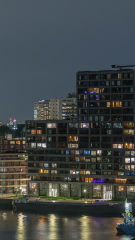 Panoramic aerial timelapse of Katendrecht peninsula at night and Maashaven harbour in Rotterdam, The Netherlands. Illuminated city skyline, modern skyscrapers and Euromast, houses on a waterfront