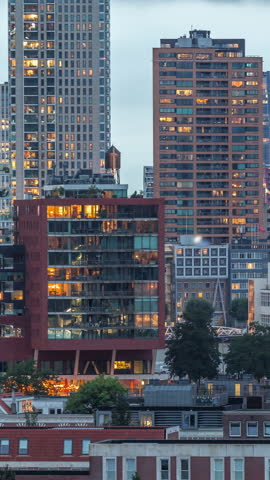 Aerial day to night transition timelapse of Katendrecht peninsula and Maashaven harbour in Rotterdam, The Netherlands. City skyline modern skyscrapers with glowing and blinking windows after sunset