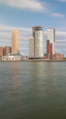 Panorama showing Rotterdam skyline timelapse from Nieuwe Maas River bank to Wilhelminapier and Kop van Zuid. Modern skyscrapers, ship terminal and Erasmus Bridge, waterfront with boats passing by