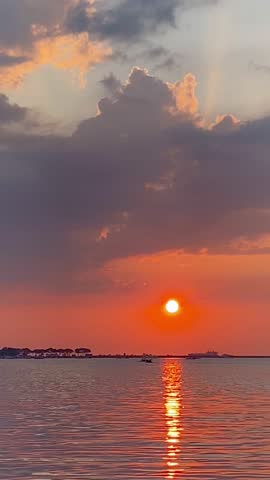 Stunning Orange Sunset over Tranquil Waters with Sun Reflecting Brightly