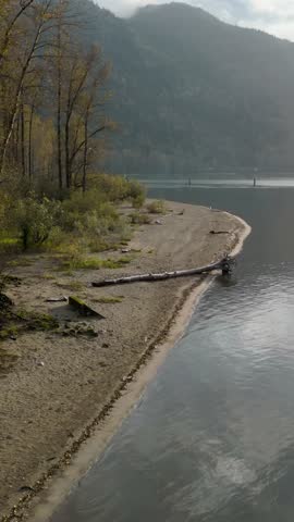Peaceful Sandy Shoreline by Calm Lake Waters with Majestic Mountains, British Columbia, Canada