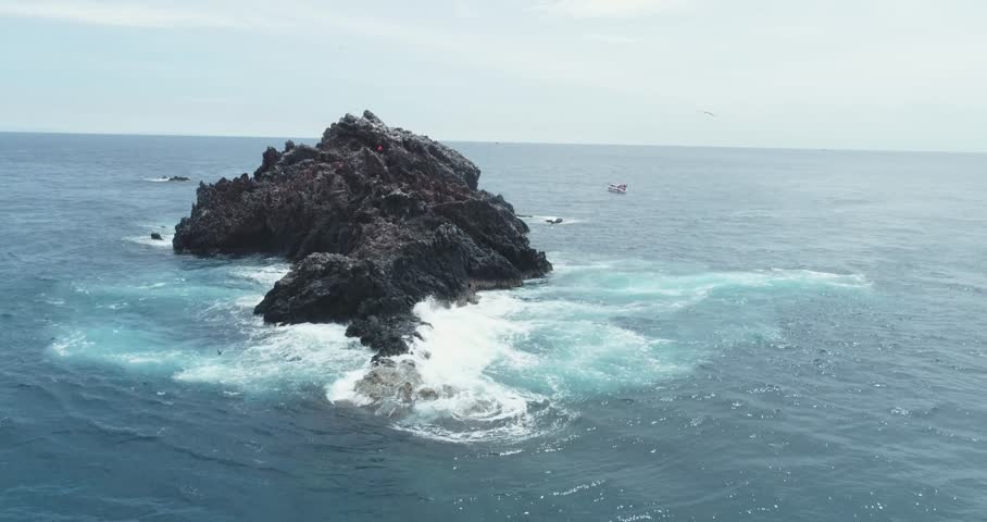 Drone boom up from sea surface with birds flying over revealing small island