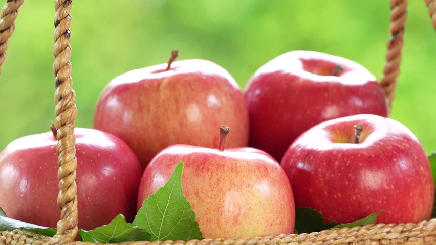 Red Fuji Apple on blurred greenery background, Fresh Pink Japanese Apple in Bamboo basket on wooden table in garden.