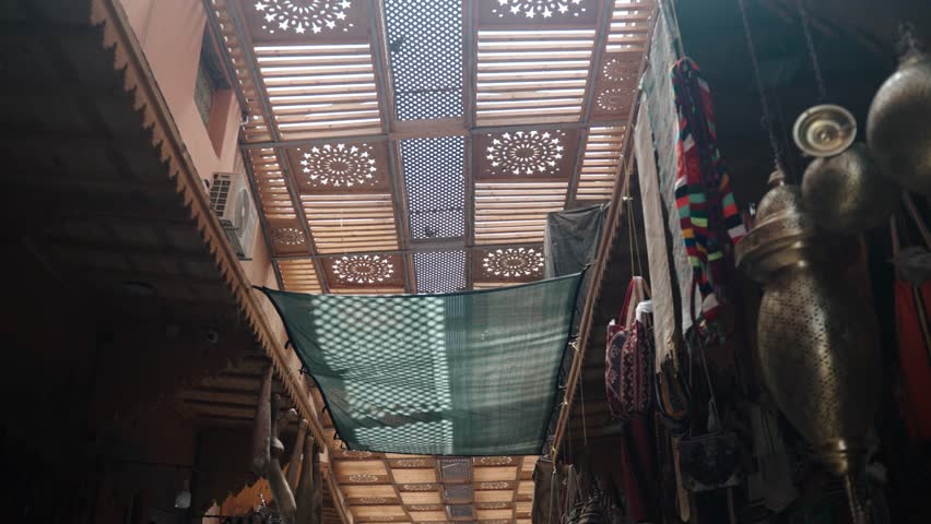 Wooden roof with brass lanterns and fabrics inside Marrakech Medina souk.