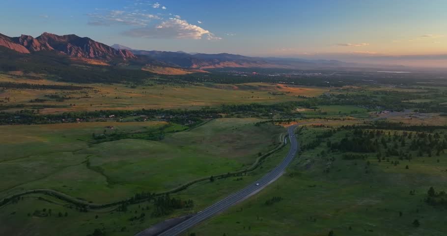 Flatirons Front Range Boulder Chautauqua Park morning sunrise aerial drone Colorado spring summer pink cloud first light on red slanted Rocky Mountains highway 36 car traffic forward pan up motion
