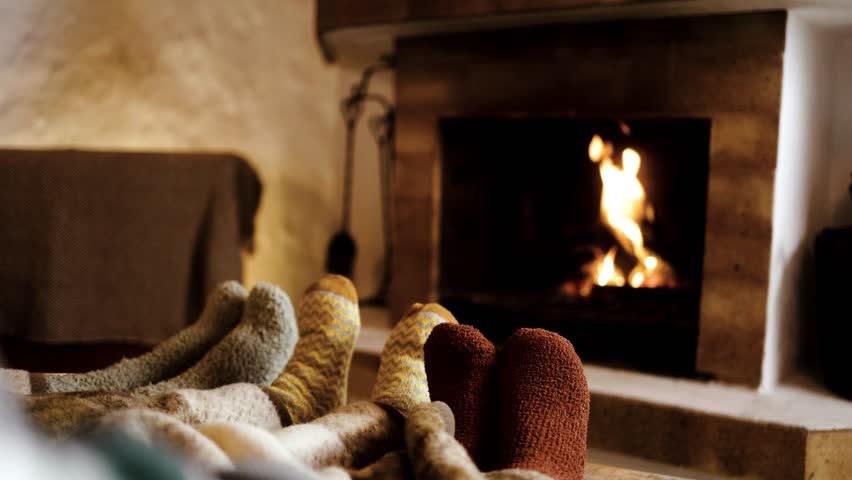 Feet in wool socks near fireplace in winter - Cozy christmas holiday home relaxation