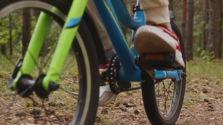 Detail close up of boy sneaker foot pressing pedal on forest bike ride Clip highlights motion training endurance and childhood fitness. High quality 4k footage
