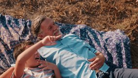 Grandfather and grandson lie on a blanket and point at the sky. They enjoy a beautiful sunny day together. Family time in nature. - Powered by Shutterstock - Get 15% off with code: PIKWIZARD15