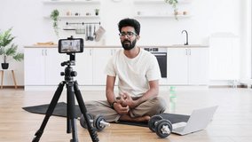 Man sitting on yoga mat recording fitness blog at home using dumbbell and tripod camera setup. Concept highlights health, fitness, and modern lifestyle promoting home-recorded fitness video - Powered by Shutterstock - Get 15% off with code: PIKWIZARD15