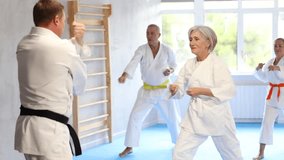 Diligent old man attendee of karate classes practicing kata standing in row with others in sports hall - Powered by Shutterstock - Get 15% off with code: PIKWIZARD15