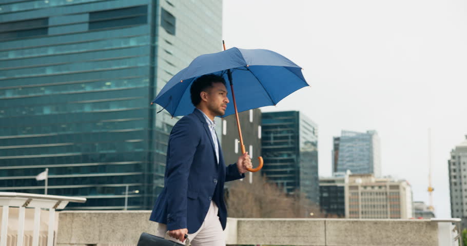 City, walking and lawyer nervous with umbrella for travel, morning commute and journey to work. Businessman, attorney and person with weather anxiety in urban town for trip with metro and opportunity