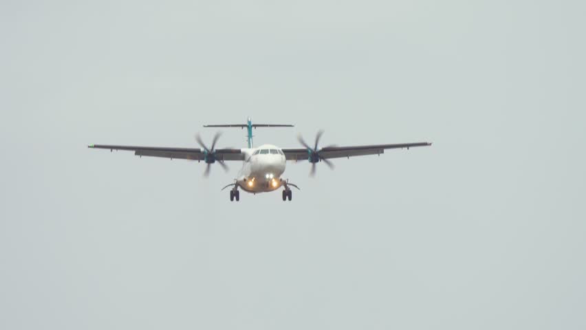 Propeller plane gently approaching for landing with gear extended. Aircraft steadily descending in cloudy skies with wheels down. Smooth approach showcasing calm landing procedure