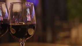 Two people clink red wine glasses in warm, softly lit hotel bar with blurred television - Powered by Shutterstock - Get 15% off with code: PIKWIZARD15