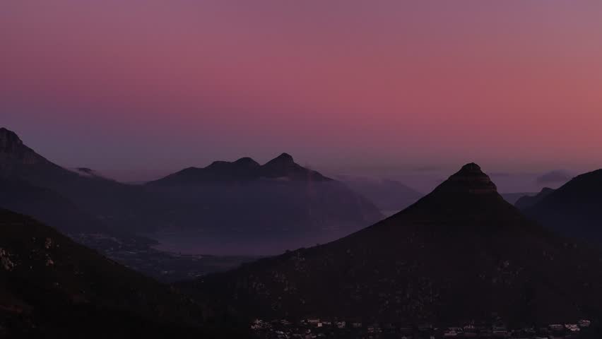 Aerial view of Lions Head and mountains shrouded in early morning mist under a vibrant pink and purple sky, Cape Town, Western Cape, South Africa.