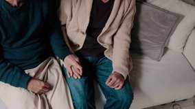 A gay couple sits together on a sofa, holding hands and sharing an intimate moment of affection. This clip portrays a sense of love, comfort, and togetherness. - Powered by Shutterstock - Get 15% off with code: PIKWIZARD15