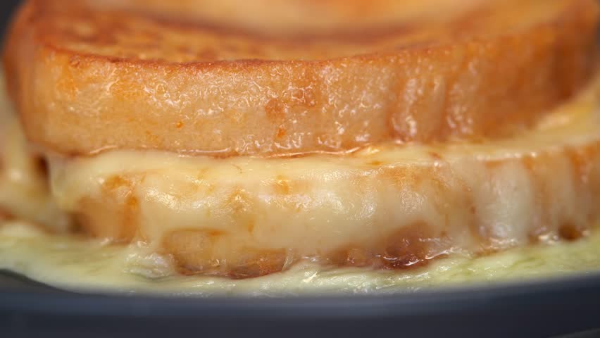 Close up of knife cuts sandwich baked in egg with cheese and ham. French toast with melted cheese for breakfast. Food background