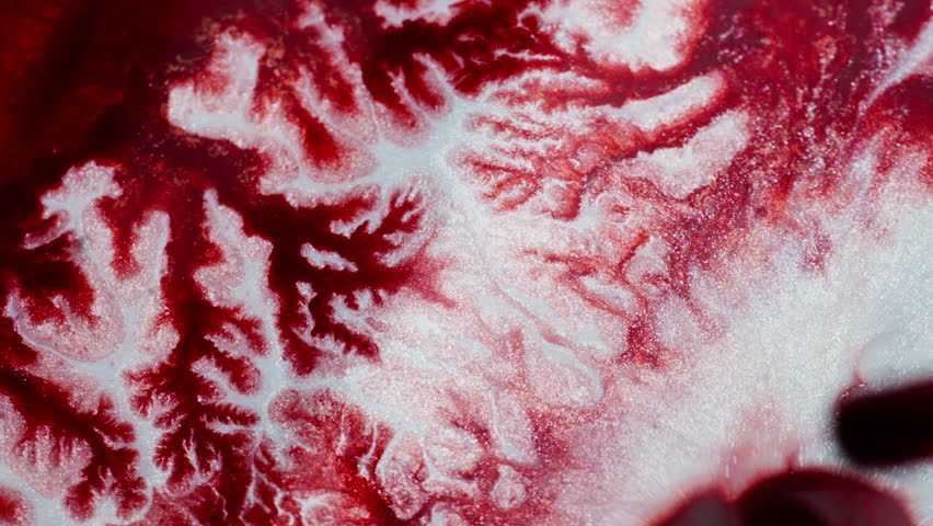 Thick ink moving slowly, creating a marbled red background. Macro view
