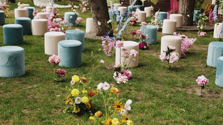 Outdoor wedding ceremony, wedding decor. The ceremony is beautifully decorated with colorful flowers and colored poufs.