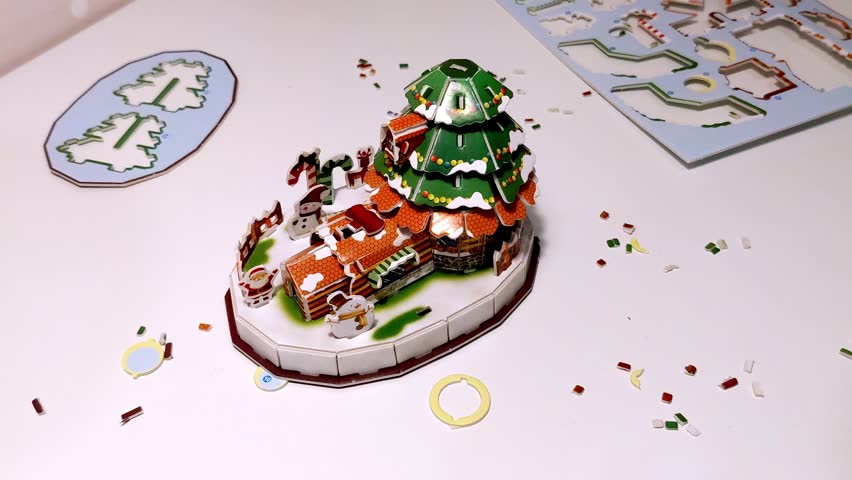 A child adds final tiny decorations to a completed Christmas craft. The step by step project is finished