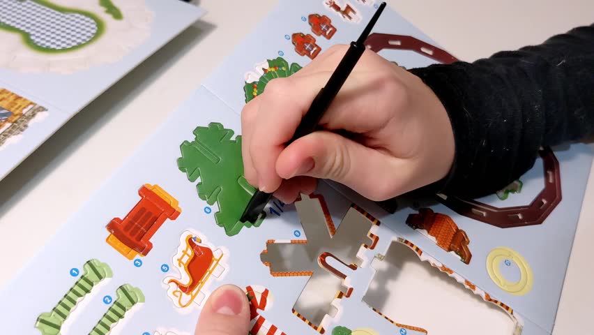 Child uses a tool to push out a Christmas tree from a cardboard craft kit. A step by step process