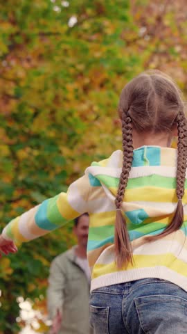 Happy family playing in autumn park. Dad throws daughter up spins together in nature park. Dad raises girl. Dad plays with his little daughter who is spinning in his arms autumn park. Childhood dream