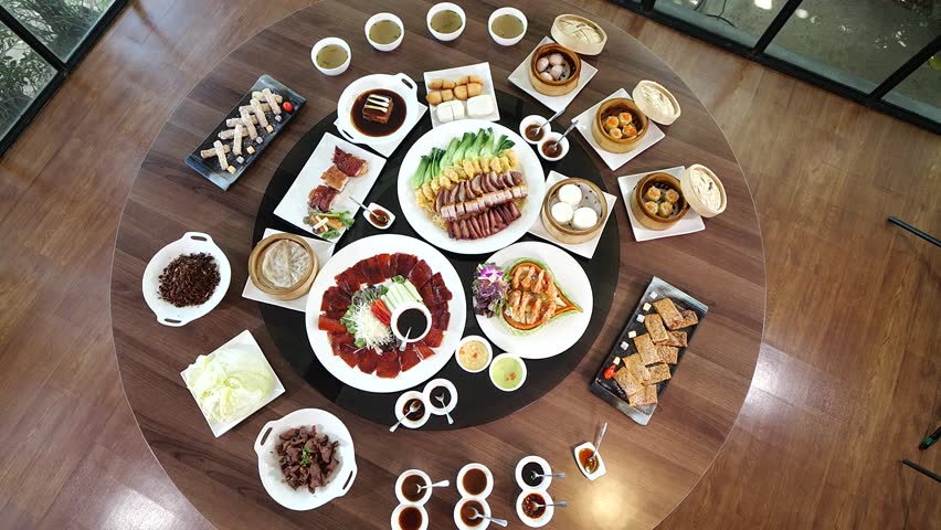 A luxurious Chinese banquet spread displayed on a round dining table, featuring Peking duck, dim sum, roasted meats, and assorted side dishes for a festive family meal.