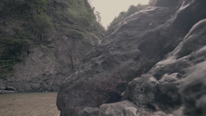 A beautiful waterfall cascading down a rocky cliff into a clear pool, surrounded by lush greenery.