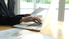 A businessman calculates finances using a calculator, analyzing charts and graphs on documents, while working with laptop and smartphone in office. - Powered by Shutterstock - Get 15% off with code: PIKWIZARD15