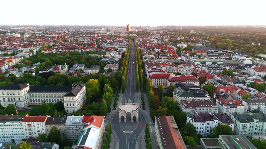 Drone footage of Siegestor in Munich, capturing historic triumphal arch, Bavarian landmarks, Maxvorstadt and Schwabing districts at golden hour, ideal for cinematic cityscape and travel videos