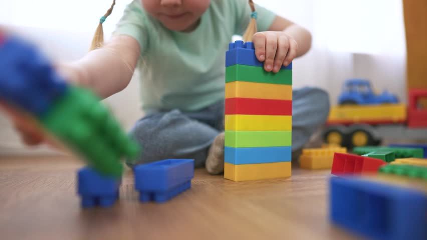 Young girl playing with her toys. Child is constructor of a game of toys. A girl plays with toys in a toys kindergarten. A little girl enjoying her lifestyle.