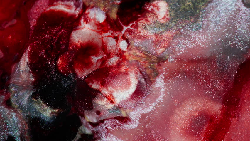 Expanding wave of thick red ink with glitter. Macro view