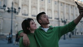 Romantic couple posing for selfie outside Royal Palace, smiling with joy. Concept of digital lifestyle, love, travel, and authentic bonding abroad - Powered by Shutterstock - Get 15% off with code: PIKWIZARD15
