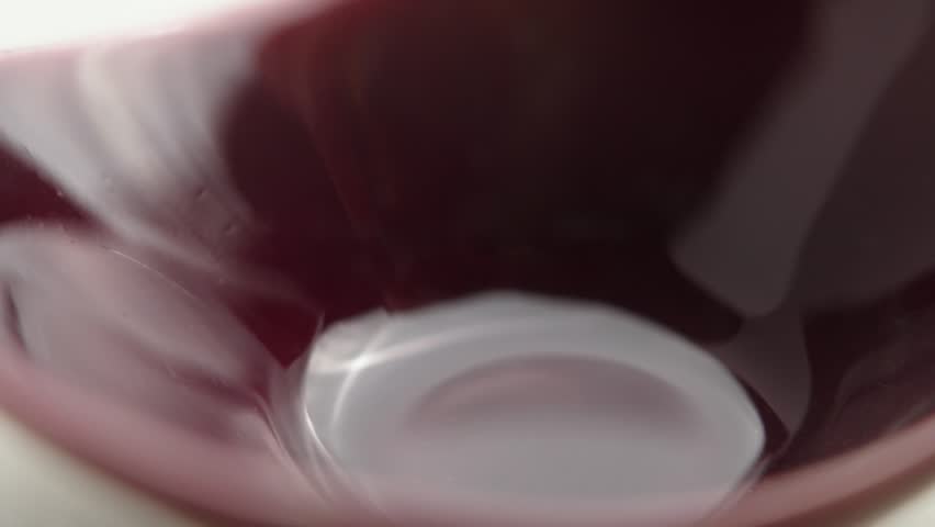 Medicinal capsules filled with powdered extract falling into a red ceramic bowl in slow motion. Macro shot