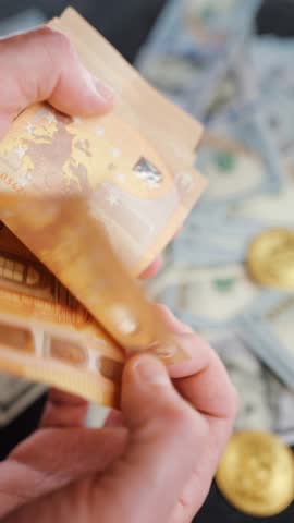Male hands counting euro bills. US dollar bills are on the background